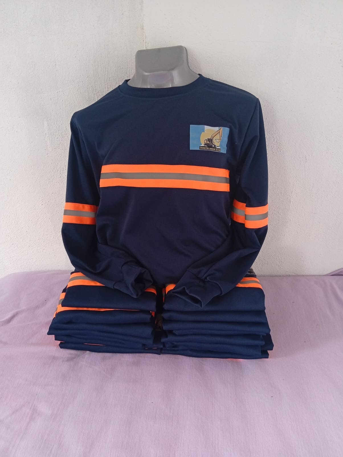 Playera industrial azul marino de manga larga con franjas reflectivas y logo personalizado, fotografía de Uniformes Evolution